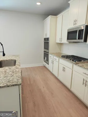 a kitchen with granite countertop white cabinets and stainless steel appliances