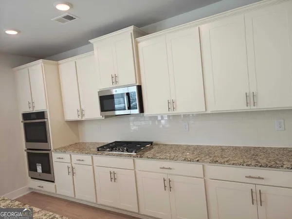 a kitchen with granite countertop white cabinets and stainless steel appliances