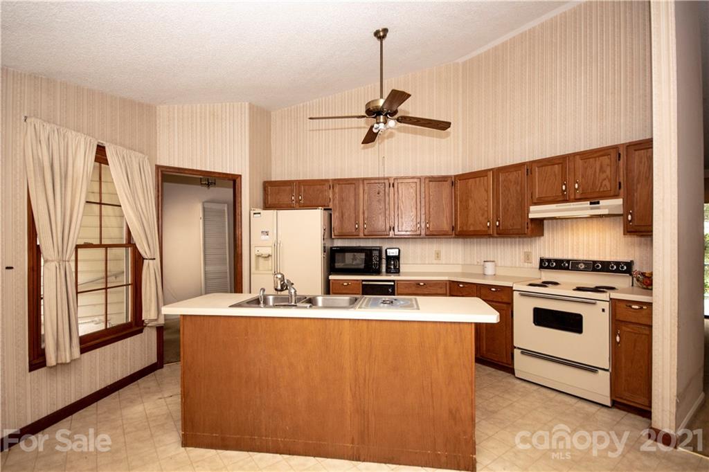 449 Oak Ridge Drive Clyde, NC 28721 - Photo 4 of 18 a kitchen with stainless steel appliances granite countertop a stove a sink dishwasher a refrigerator and a dining table with wooden floor
