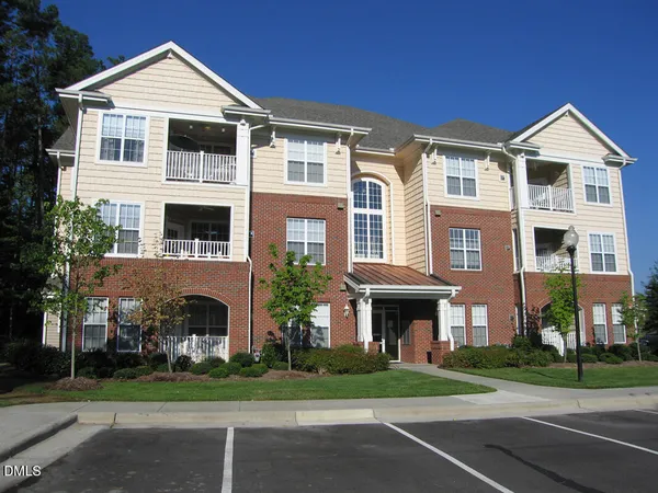 a large white building with a yard and plants