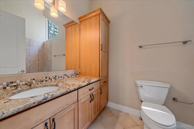 a bathroom with a granite countertop sink mirror vanity and toilet