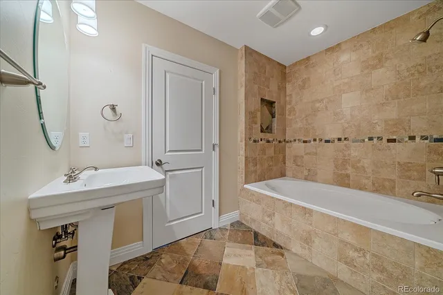a bathroom with a tub sink and mirror
