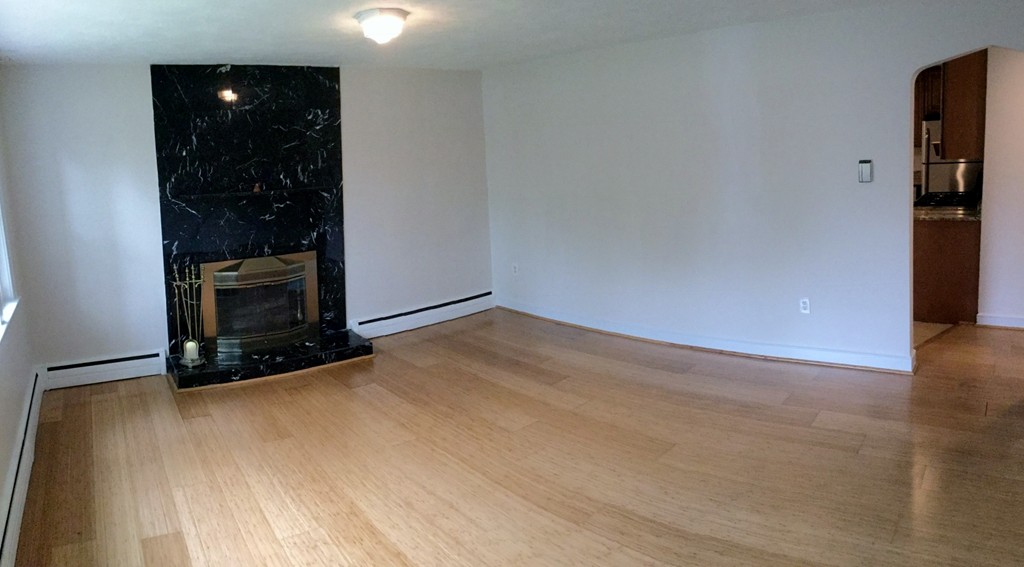 1247 Trapelo Road Waltham, MA 02451 - Photo 4 of 28 a view of an empty room with wooden floor and a fireplace