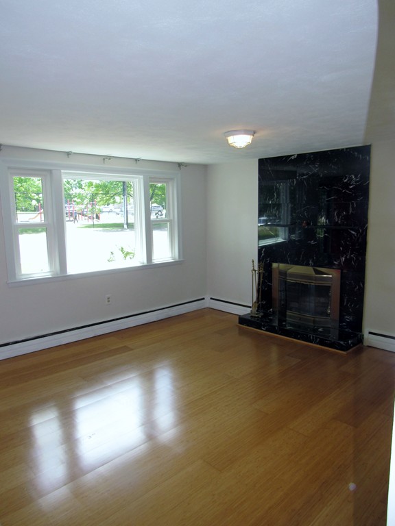 1247 Trapelo Road Waltham, MA 02451 - Photo 6 of 28 an empty room with a fireplace and windows