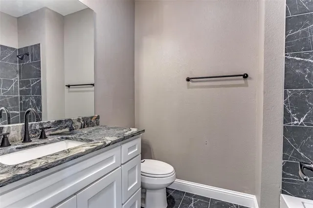 a bathroom with a granite countertop sink toilet and a mirror