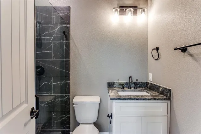 a bathroom with a granite countertop toilet a sink and a mirror