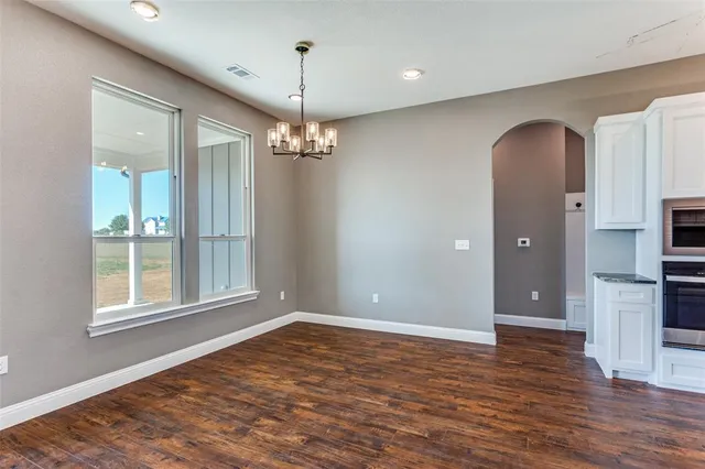 an empty room with wooden floor mirror and windows