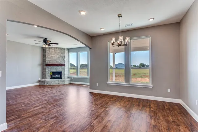 a view of an empty room with wooden floor fireplace and a window