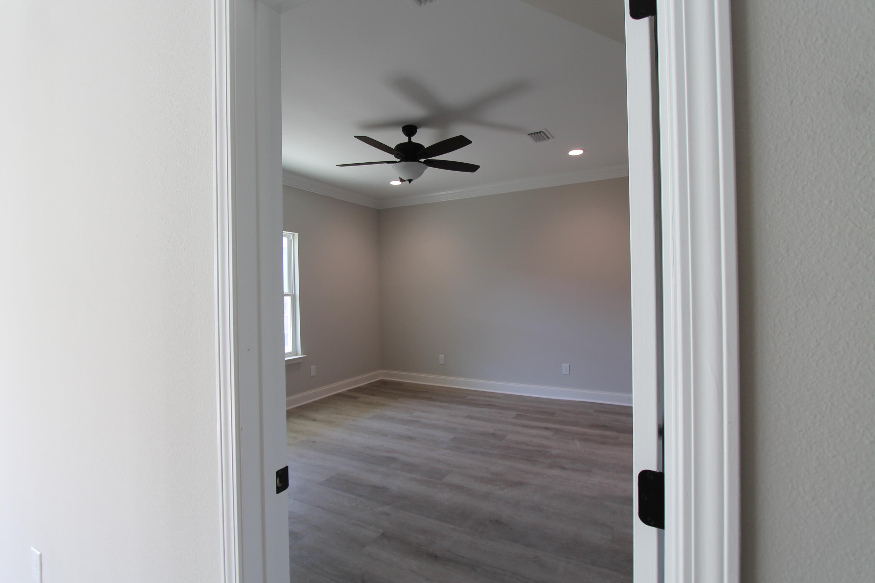 2135 Nina Street Navarre, FL 32566 - Photo 6 of 7 an empty room that has a chandelier fan and wooden floor