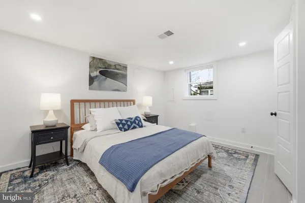 a bedroom with a bed and a lamp on dresser