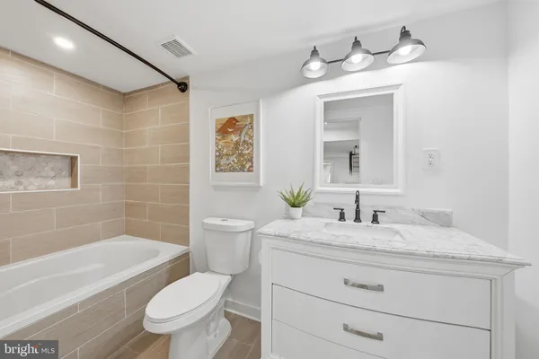 a bathroom with a granite countertop sink toilet a large mirror a bathtub and shower