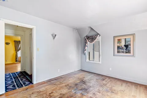 a view of a bedroom with wooden floor and a window