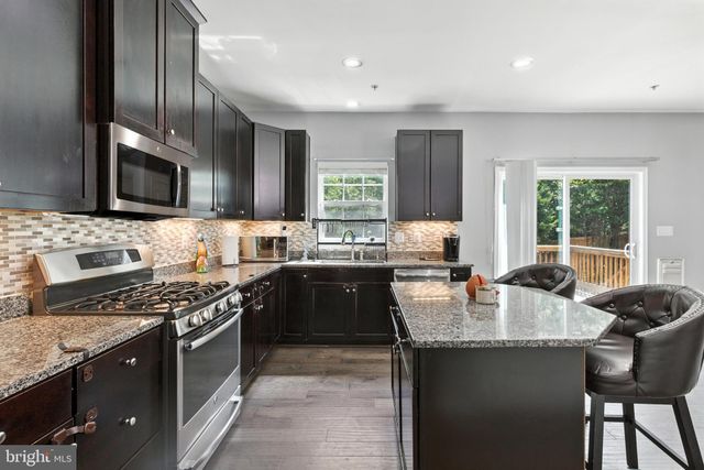 a kitchen with granite countertop stainless steel appliances a stove sink microwave and cabinets