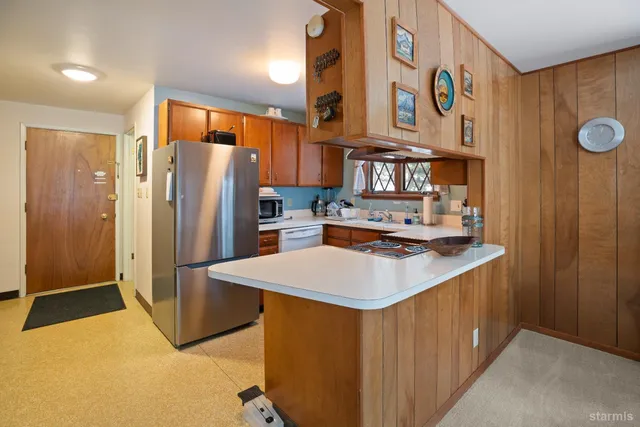 a kitchen with stainless steel appliances granite countertop a refrigerator a stove and a sink with wooden cabinets