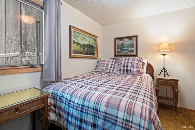 a bedroom with a bed and a lamp on dresser