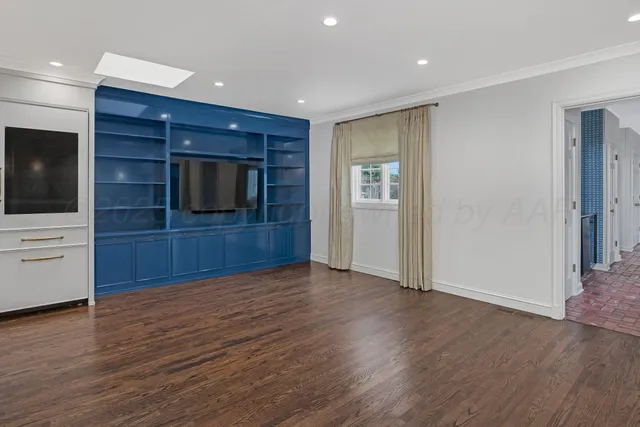 a view of an empty room with wooden floor and closet