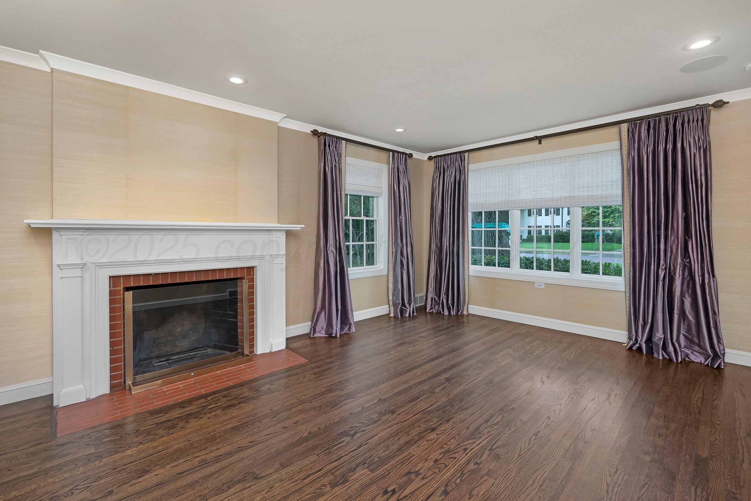 3003 South Hughes Street Amarillo, TX 79109 - Photo 4 of 76 a view of an empty room with wooden floor fireplace and a window