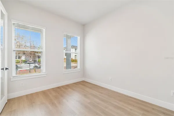 an empty room with wooden floor and windows