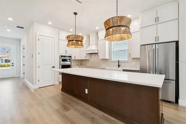 a kitchen with kitchen island a sink a stove and wooden floors