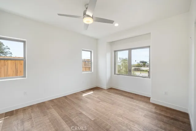a view of an empty room with window and wooden floor