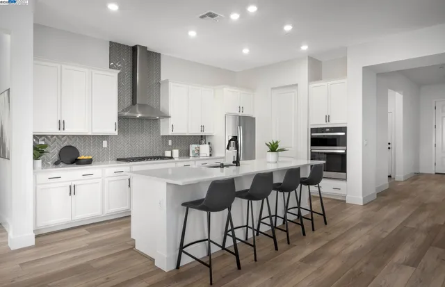 a kitchen with stainless steel appliances kitchen island granite countertop a table chairs sink and cabinets