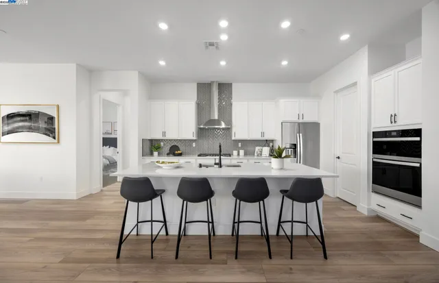 a kitchen with stainless steel appliances granite countertop a table and chairs in it