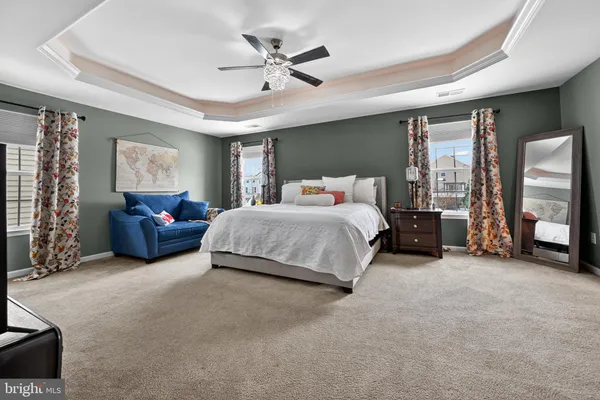 a spacious bedroom with a bed a couch and a chandelier