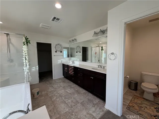 a large bathroom with a granite countertop double vanity sink a large mirror and a bathtub