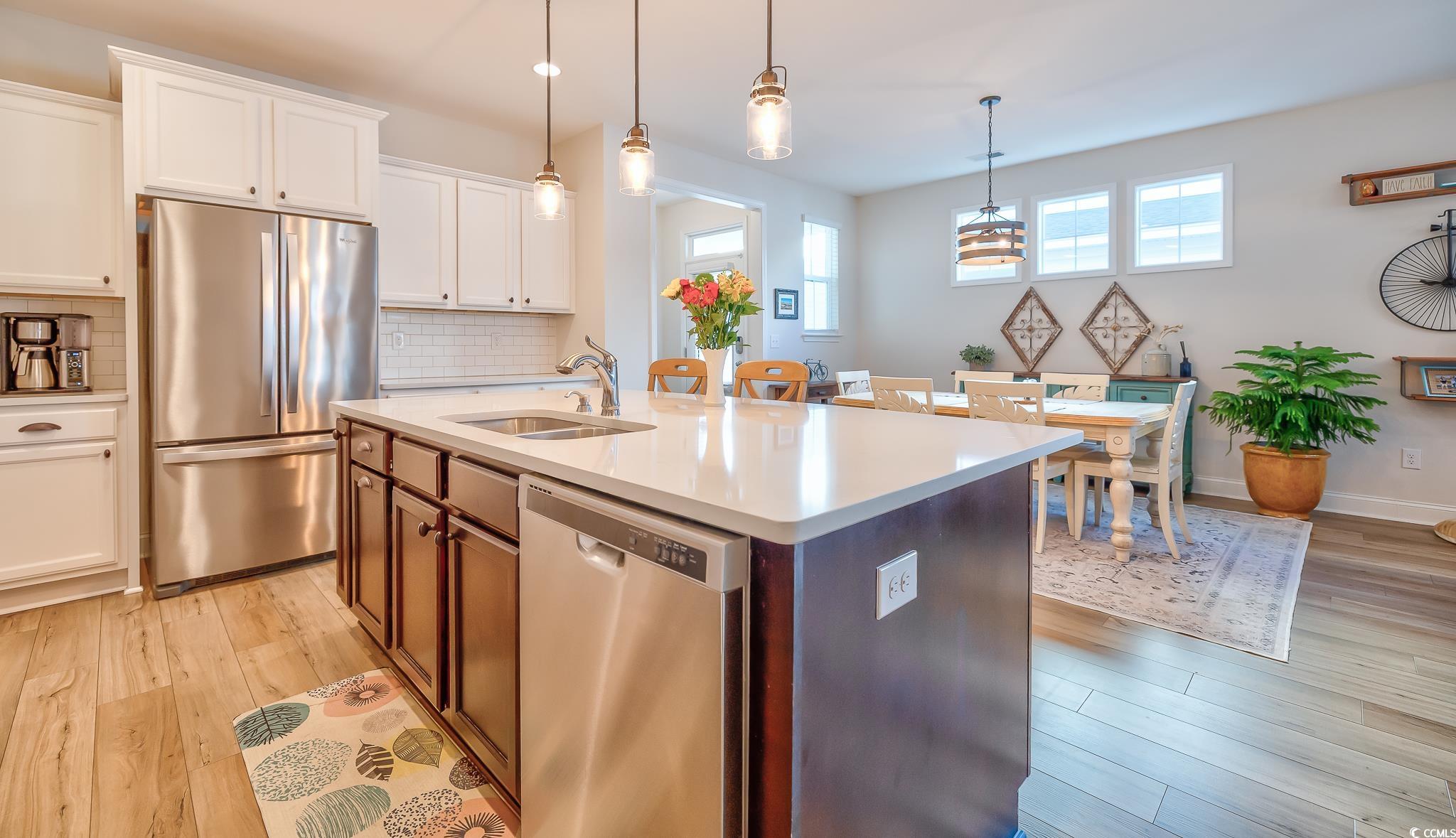 2052 Silver Island Way Murrells Inlet, SC 29576 - Photo 16 of 24 Kitchen featuring stainless steel appliances, white cabinetry, hanging light fixtures, a kitchen island with sink, and light wood-style flooring