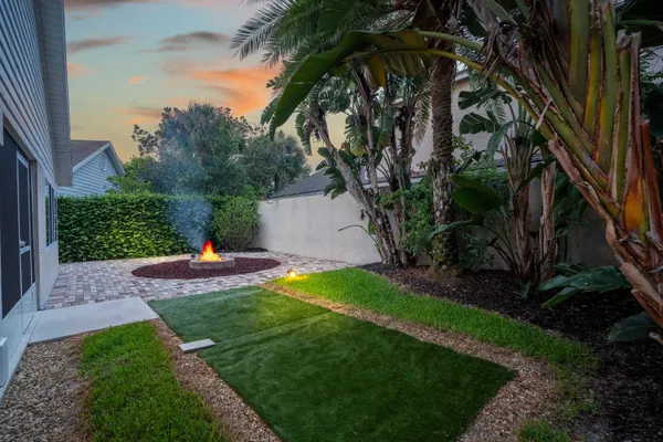a view of a backyard with a fountain plants and large tree