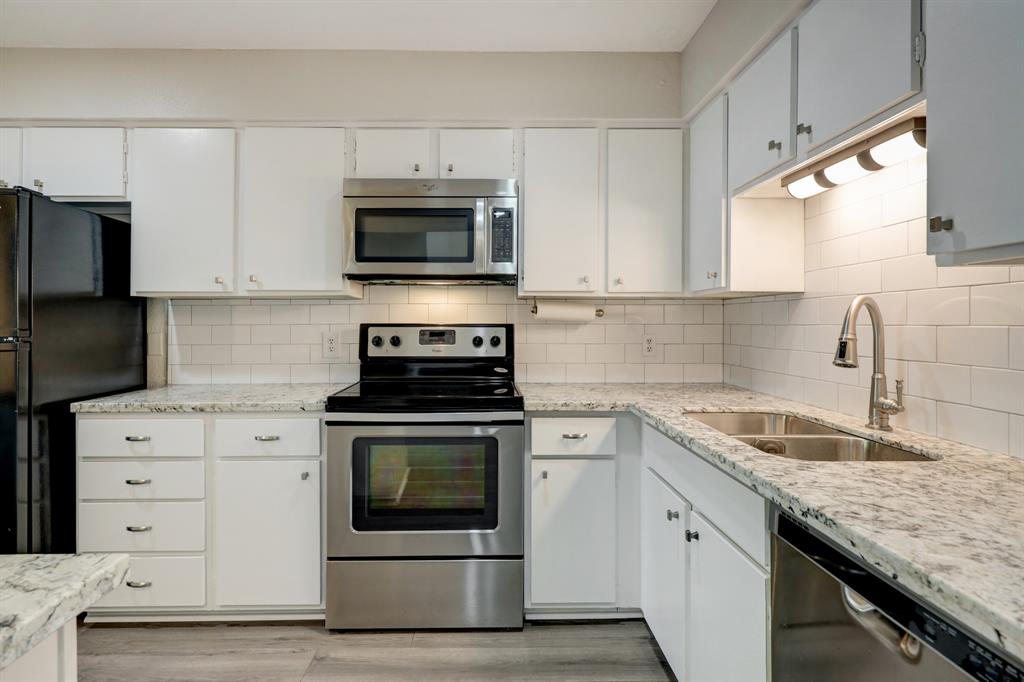 a kitchen with granite countertop a sink dishwasher a stove and a microwave oven with cabinets