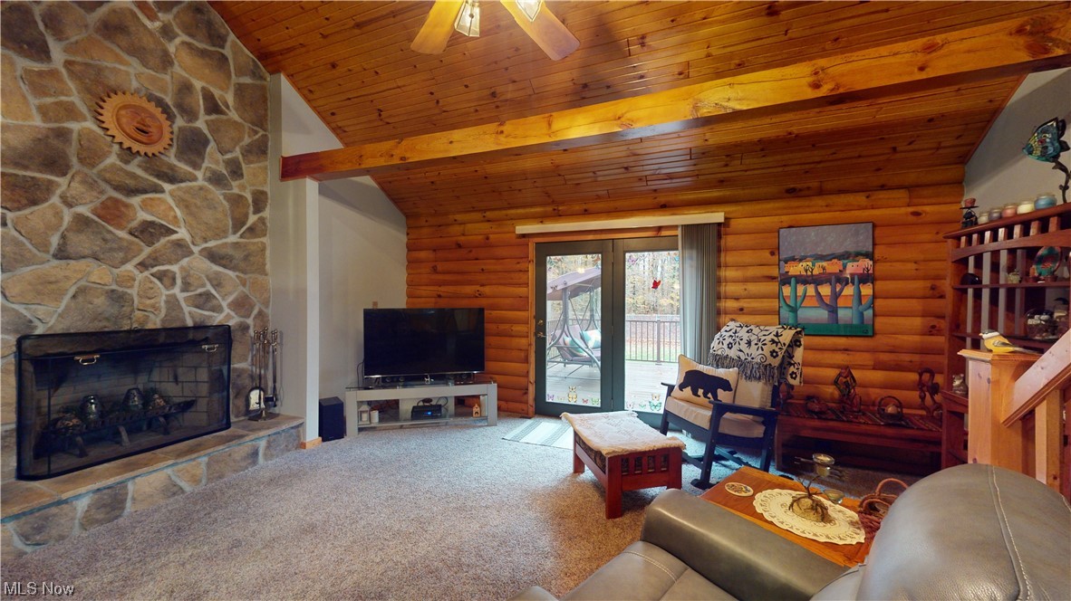 4308 Lyntz Road Warren, OH 44481 - Photo 20 of 34 Carpeted living room with wood ceiling, a fireplace, log walls, vaulted ceiling with beams, and ceiling fan