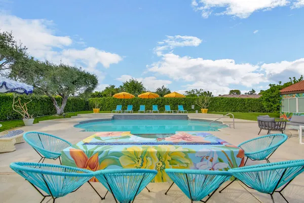 a view of a swimming pool with lawn chairs and plants