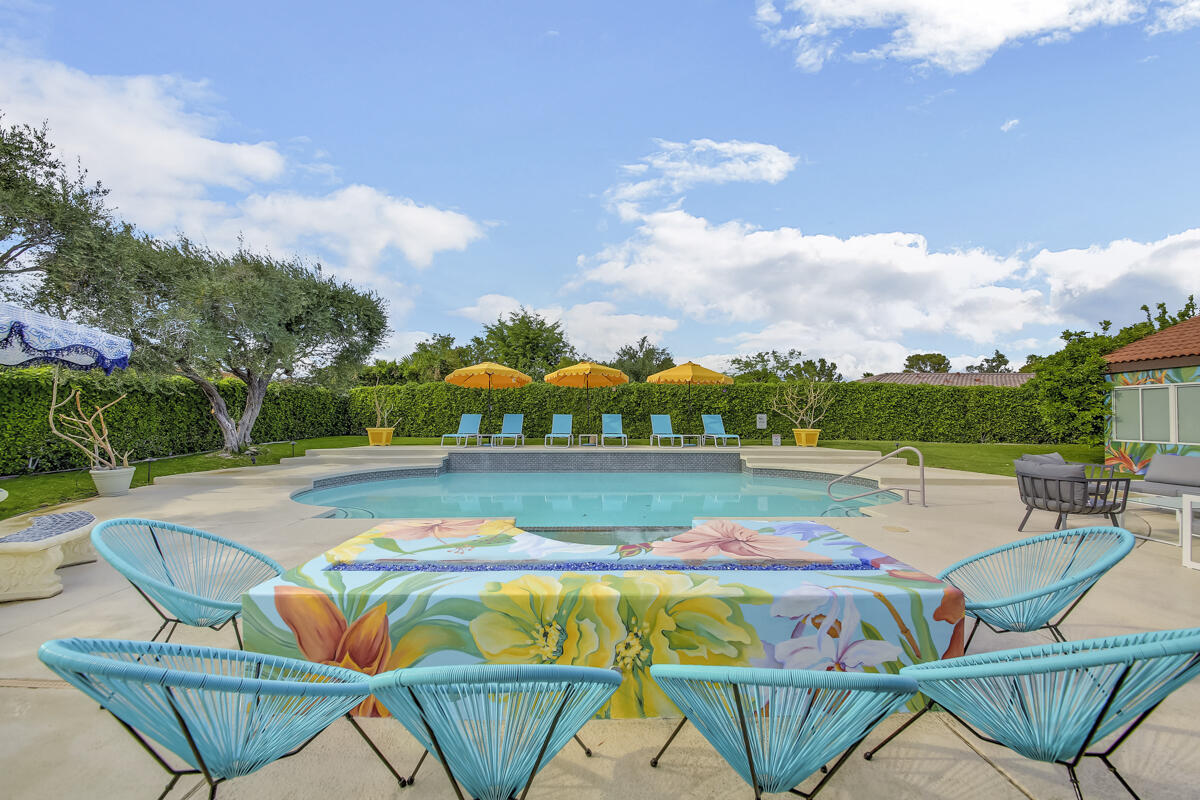 a view of a swimming pool with lawn chairs and plants