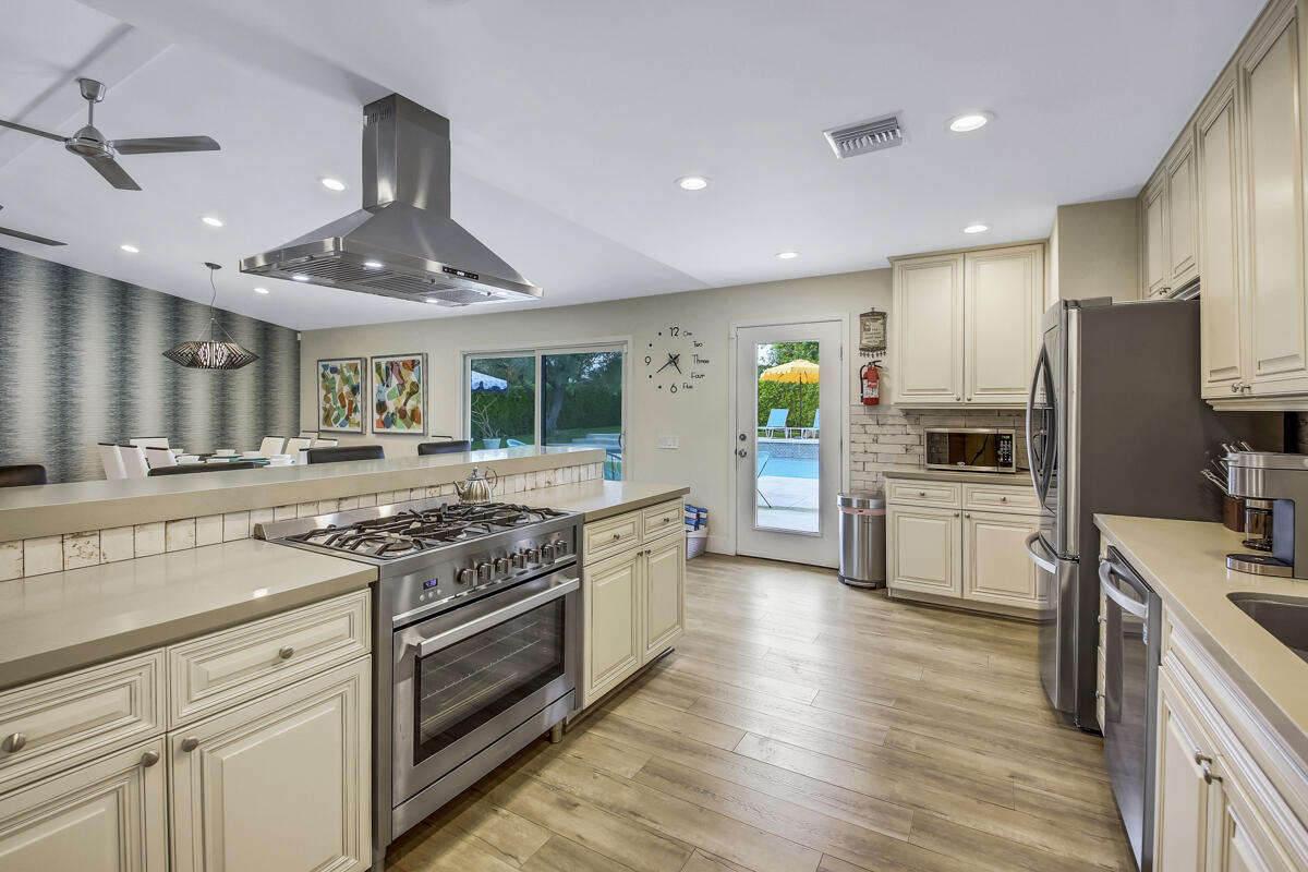 2230 Tamarisk Road Palm Springs, CA 92262 - Photo 43 of 66 a kitchen with stainless steel appliances granite countertop a stove top oven a sink dishwasher a refrigerator and white cabinets with wooden floor