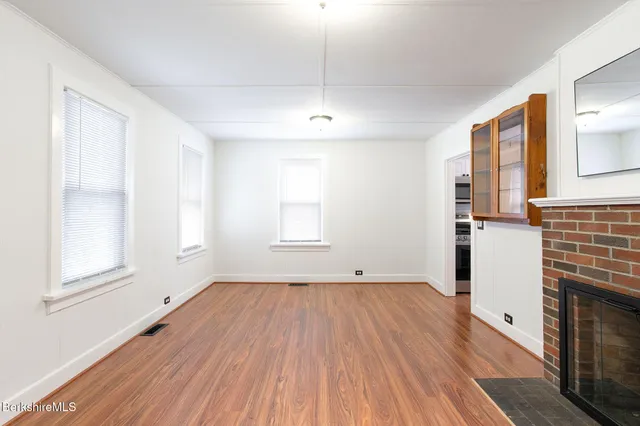 an empty room with wooden floor and a fireplace