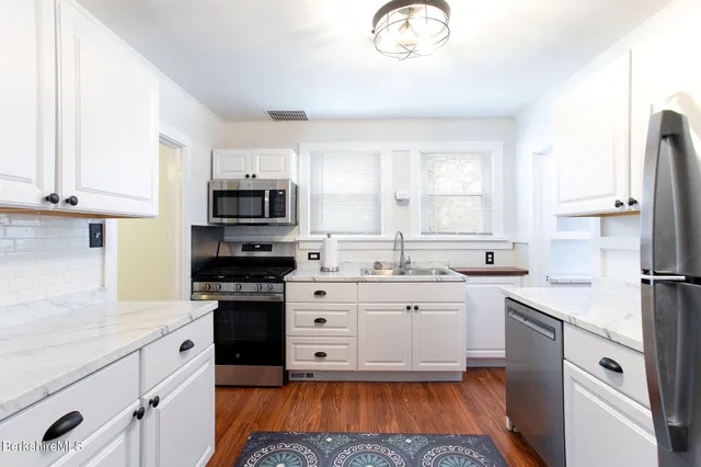a view of a kitchen with wooden floor and electronic appliances