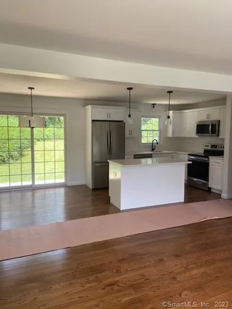 a view of a kitchen with kitchen island a counter top space a sink stainless steel appliances and cabinets