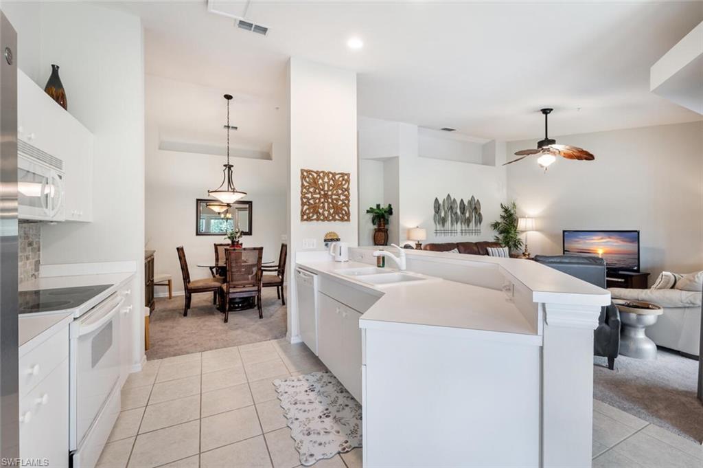 2895 Cypress Trace Circle, Unit 202 Naples, FL 34119 - Photo 12 of 30 a large white kitchen with sink and washing machine