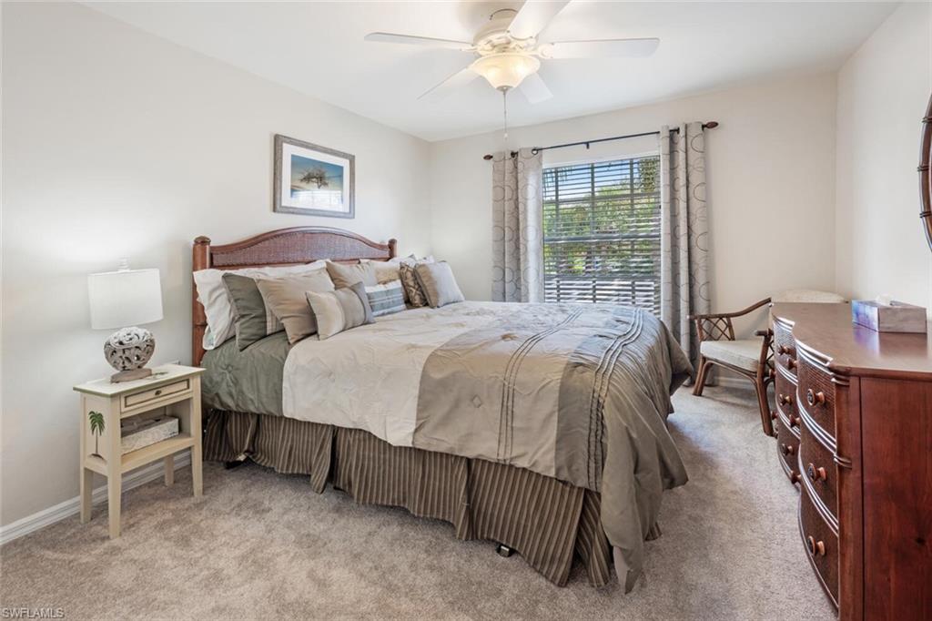 2895 Cypress Trace Circle, Unit 202 Naples, FL 34119 - Photo 20 of 30 a bedroom with a bed and a chandelier