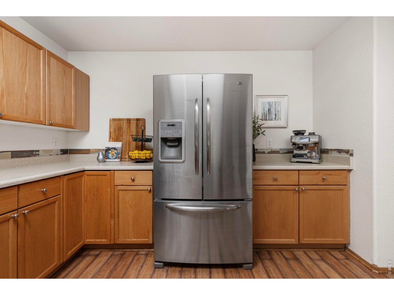 6531 St Vrain Ranch Boulevard Firestone, CO 80504 - Photo 13 of 30 a kitchen with stainless steel appliances granite countertop a refrigerator a sink dishwasher and white cabinets with wooden floor