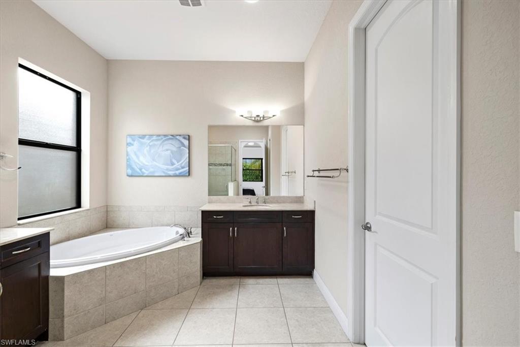 1509 Serrano Circle Naples, FL 34105 - Photo 14 of 24 a bathroom with a bathtub a mirror a vanity and a shower