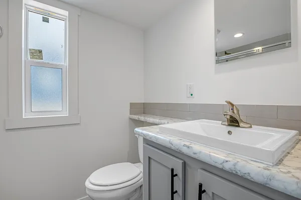a bathroom with a granite countertop sink a toilet and mirror