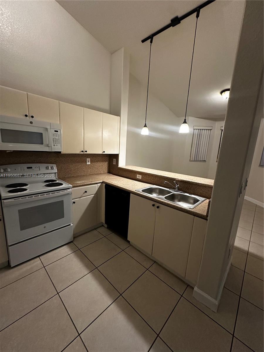 2903 Southeast 17th Avenue, Unit 209 Homestead, FL 33035 - Photo 9 of 30 a kitchen with a stove a sink and a refrigerator