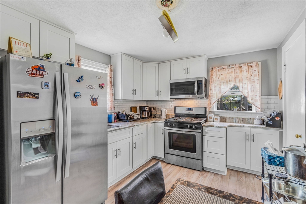 145 Maple Street Danvers, MA 01923 - Photo 8 of 27 a white kitchen with stainless steel appliances granite countertop a refrigerator a stove a sink and a window