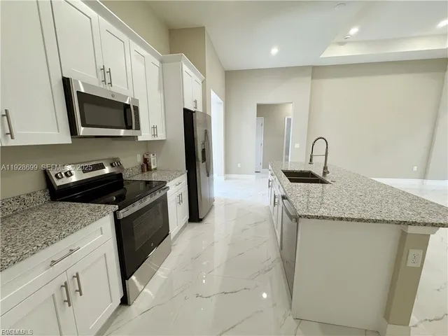 a kitchen with granite countertop a sink dishwasher stove and microwave with wooden floor