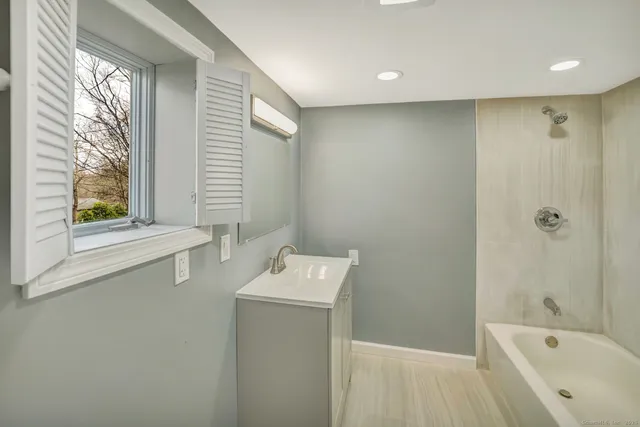 a bathroom with a bathtub sink and mirror
