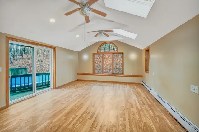 an empty room with wooden floor fan and windows
