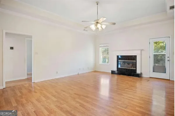 an empty room with fireplace chandelier fan and windows