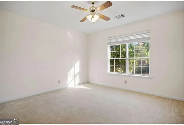 an empty room with a window and a fan